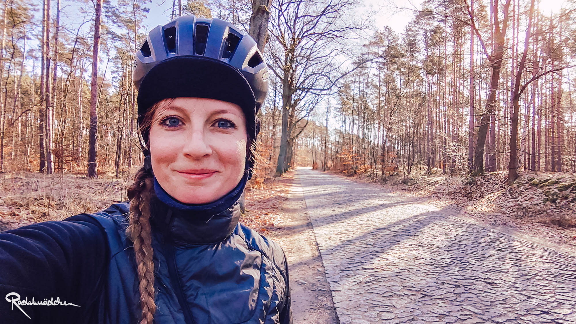 Jule in cycling apparel in the woods with cobblestone road